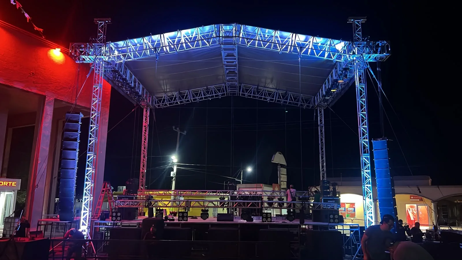 Escenario con techumbre de truss y torres de ground support, audio colgado e iluminación, montado al aire libre